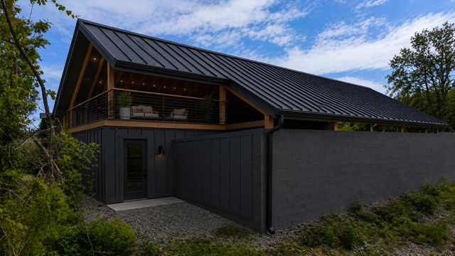 Exterior photo of Cottage Court Getaway with charcoal siding, balcony seating, and metal roof
